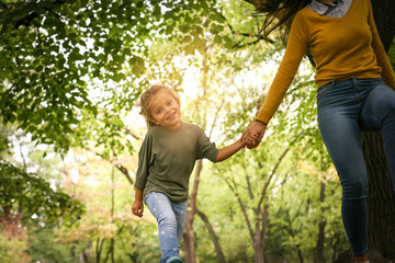 Mother an daughter in meadow. Mother and daughter holding hands and running together trough park.