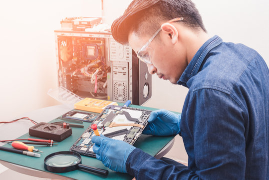 The abstract image of the asian technician repairing a tablet by screwdriver in the lab. the concept of computer hardware, mobile phone, electronic, repairing, upgrade and technology.