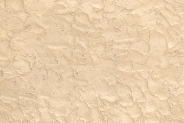 Beige surface made of the rough brushworks of plaster as a background