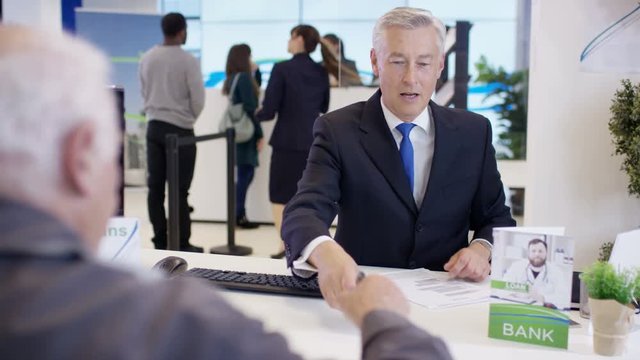  Modern city bank, adviser assisting customer & getting signature on document