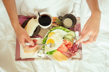 Healthy breakfast served to bed - scrambled eggs with tomatoes, cucumber and orange juice