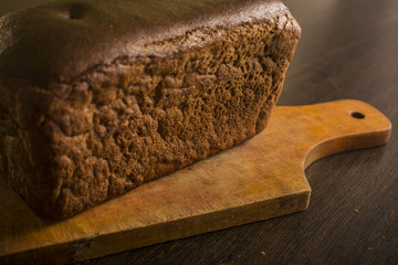 Black gray bread on a board with a knife