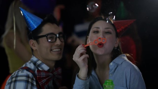  Nerdy friends at house party dancing together & blowing bubbles