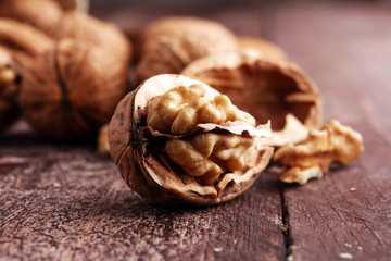 Walnut kernels and whole walnuts on rustic old wooden table.