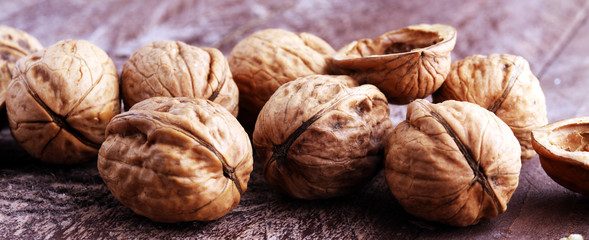 Walnut kernels and whole walnuts on rustic old wooden table.