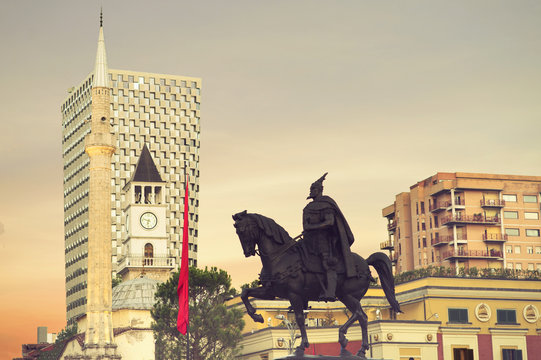 Evening and sunset sky view to main sights of Tirana at Skanderbeg square: Clock tower, mosque and modern buildings.