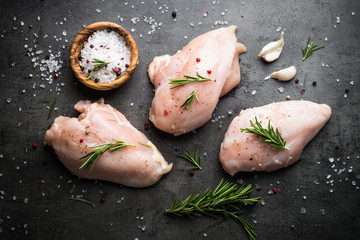 Raw chicken fillet with spices. Top view on black slate table.