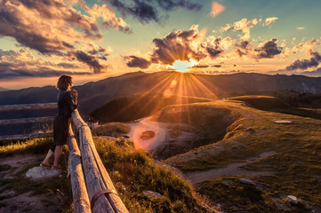 Girl watching a beautiful sunset in a peaceful and tranquil place, Mount Pizzoc summit, Veneto,...