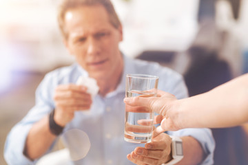 Close up of a pleasant person holding glass of water