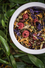 Aromatic colorful tea in pot over green leaves