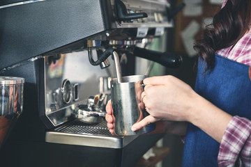 Fototapeta na wymiar Female barista making coffee using machine