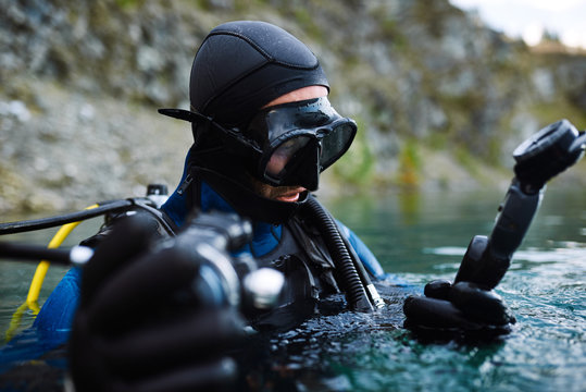 Male diver in wetsuit checking equipments before immerse