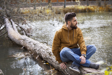 Man sitting on a tree trunk floating on the river.