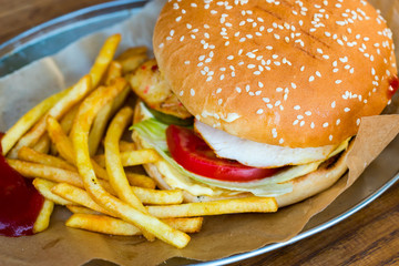 hamburger bun with sesame and chicken fillet with salad and fried potatoes