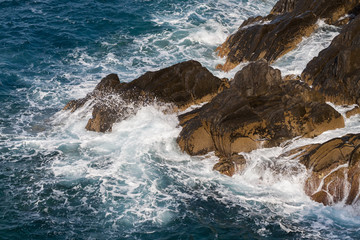 Braune Felsen im Meer Wellen Gischt Ligurien Italien