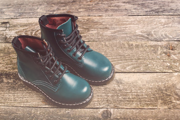 Boy's leather modern boots on dark wooden background.