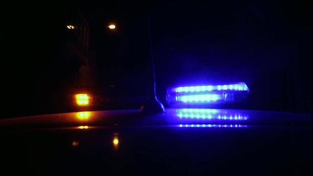 Luces Intermitentes de advertencia lanzando flash de colores en coche de la policia por la noche