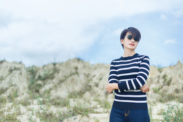 Beautiful woman in black and white sweater standing under blue sky.