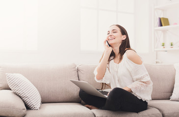 Obraz premium Young laughing woman at home with laptop and mobile