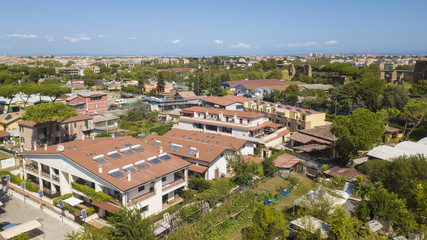 Fototapeta na wymiar Vista aerea di palazzi costruiti in mezzo ad un parco. Le finestre e i balconi delle abitazioni affacciano sugli alberi. I tetti sono fatti di tegole rosse.