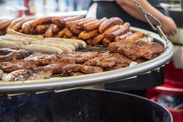 Wurst und Steaks auf Schwenkgrill beim Volksfest Imbiss Stand 