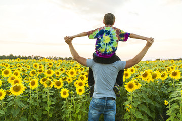 father with child in a field of blooming sunflowers , father's day