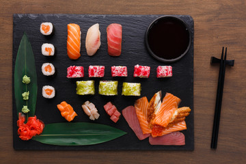 Set of sushi maki and rolls on black rustic wood, top view