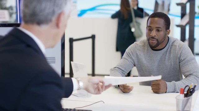 Modern city bank, adviser assisting customer & getting signature on document