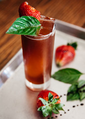 Summer alcoholic cocktail garnished with strawberries and basil