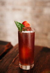 Alcoholic cocktail garnished with strawberries and basil