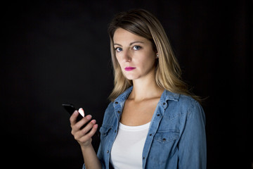 Closeup of woman holding and using modern smart phone on black background