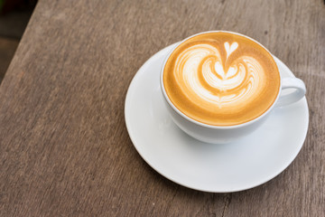 A white cup of coffee latte art on wood table