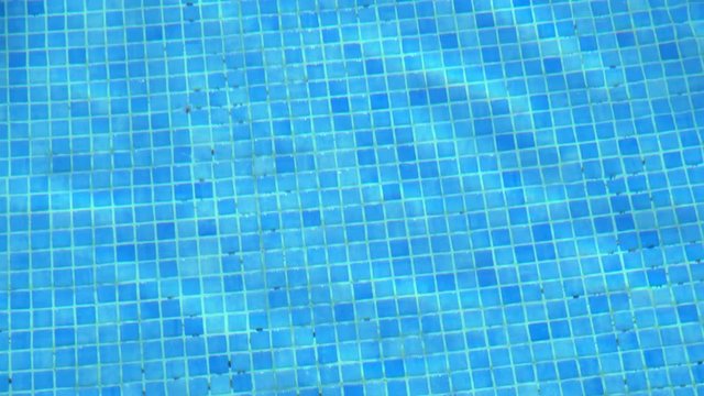 Blue tiles and pool water with close up ripples and sunshine
