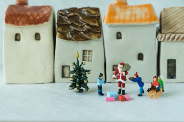 Christmas celebration story with miniature figure Santa claus giving present to happy children