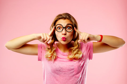 Portrait of a beautiful young woman in funny glasses over pink background