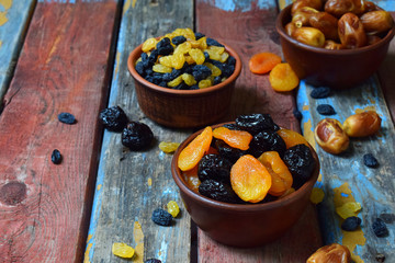 Composition from different varieties of dried fruits on wooden background - dates, apricots, prunes, raisins. Healthy food