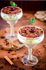 luxurious dessert Tiramisu in a glass with coffee beans and cherry on a dark background