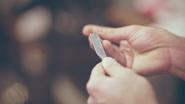 Barber preparing cutthroat razor. Close up of man hands checking straight razor. Man collecting barber razor for shaving. Straight razor shave. Barber accessories
