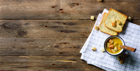 Cup of squash creamy vegetable vegetarian pumpkin carrot soup with bread crachers on wooden rustic background, copy space for your text