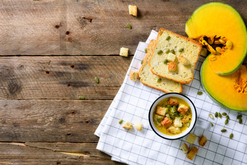 Cup of squash creamy vegetable vegetarian pumpkin carrot soup with crackers and seeds on wooden rustic background, close up, copy space