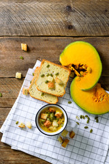 Cup of squash creamy vegetable vegetarian pumpkin carrot soup with crackers and seeds on wooden rustic background, close up, copy space