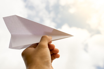 Taking flight! Hand holding paper airplane in the sky.