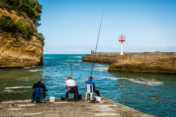 Fototapeta na wymiar 3 Biarritz fishermen sitting in the harbour