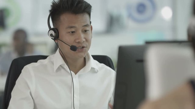 Friendly customer service operator talking to customer in busy call center