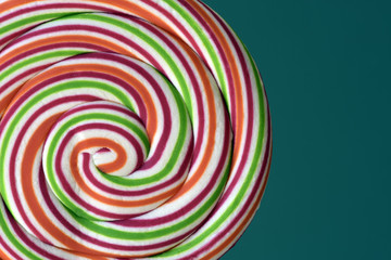 Colorful lollipop in spiral shape on green background