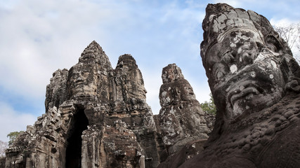 Selective Focus the Giant Statue of Yaksa or Asura (Demon) Guarded with background the Gateway of Angkor Thom Ancient City established by King Jayavarman VII, Siem Reap, Cambodia.