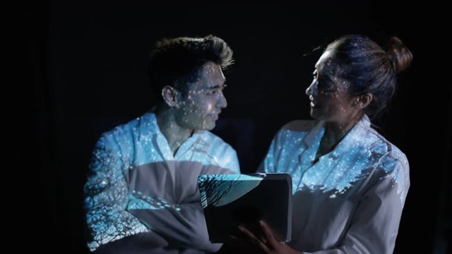 Astronomers looking at computer with telescope and stars projected onto them