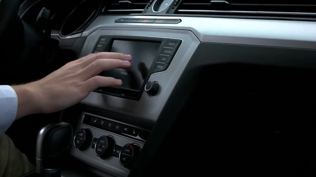 Man touches the multimedia screen in the car.