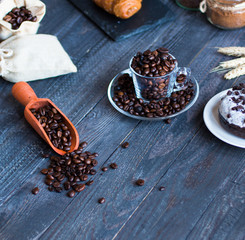 Coffee beans and cup of coffee with other components on different wooden background.
