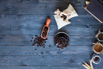 Coffee beans and cup of coffee with other components on different wooden background.